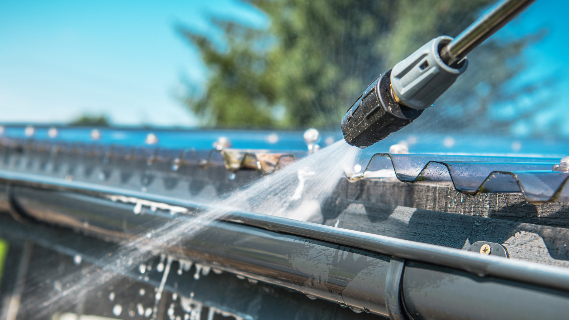 Power washer cleaning roof gutter, removing debris and buildup, maintaining roof durability and aesthetics.