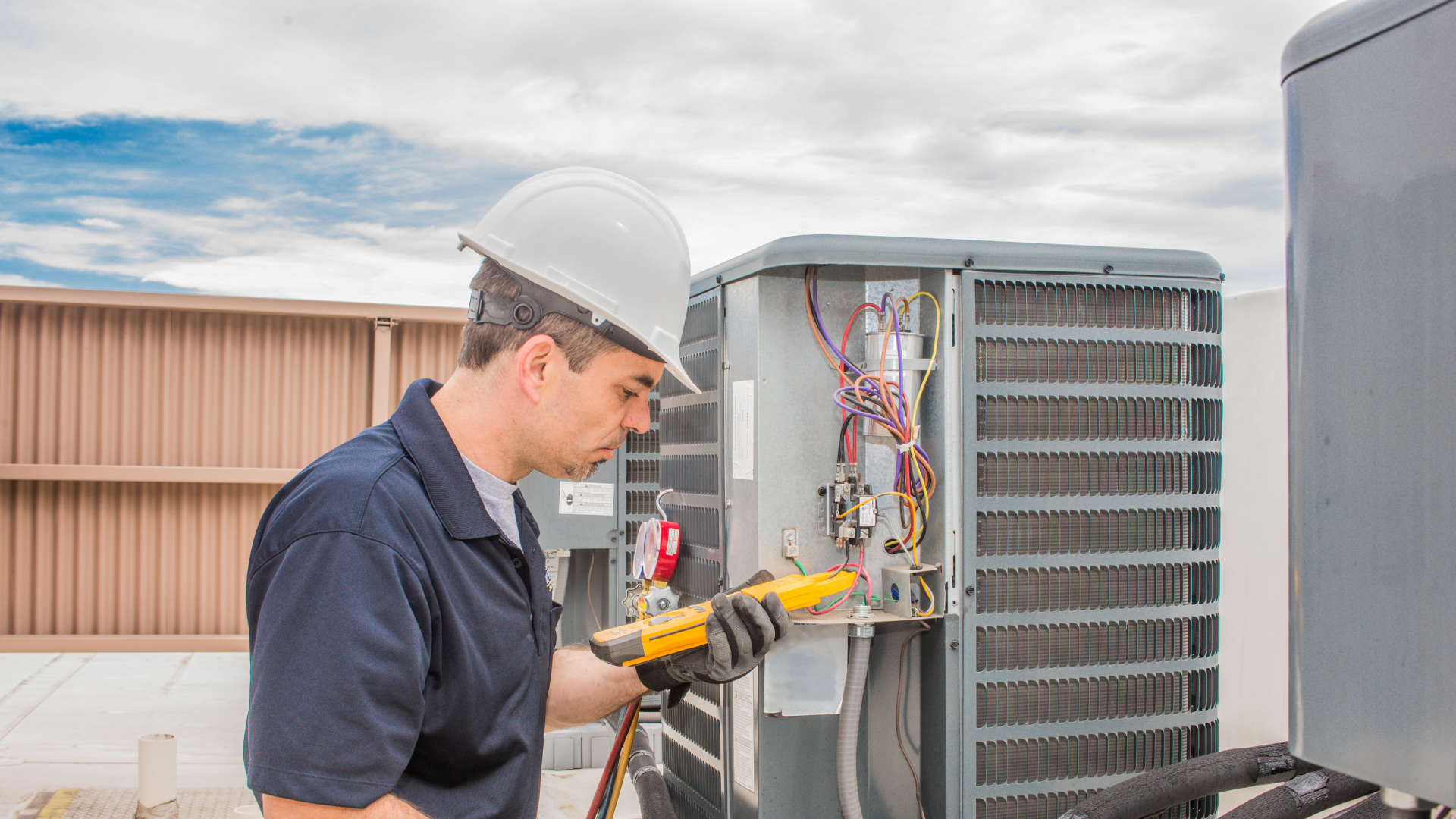 HVAC technician inspecting air conditioning unit with multimeter, focusing on electrical connections and components.