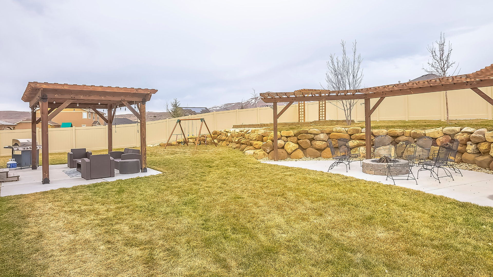 Outdoor living space featuring a pergola with seating area, fire pit, and grassy lawn, enhancing home value and curb appeal.