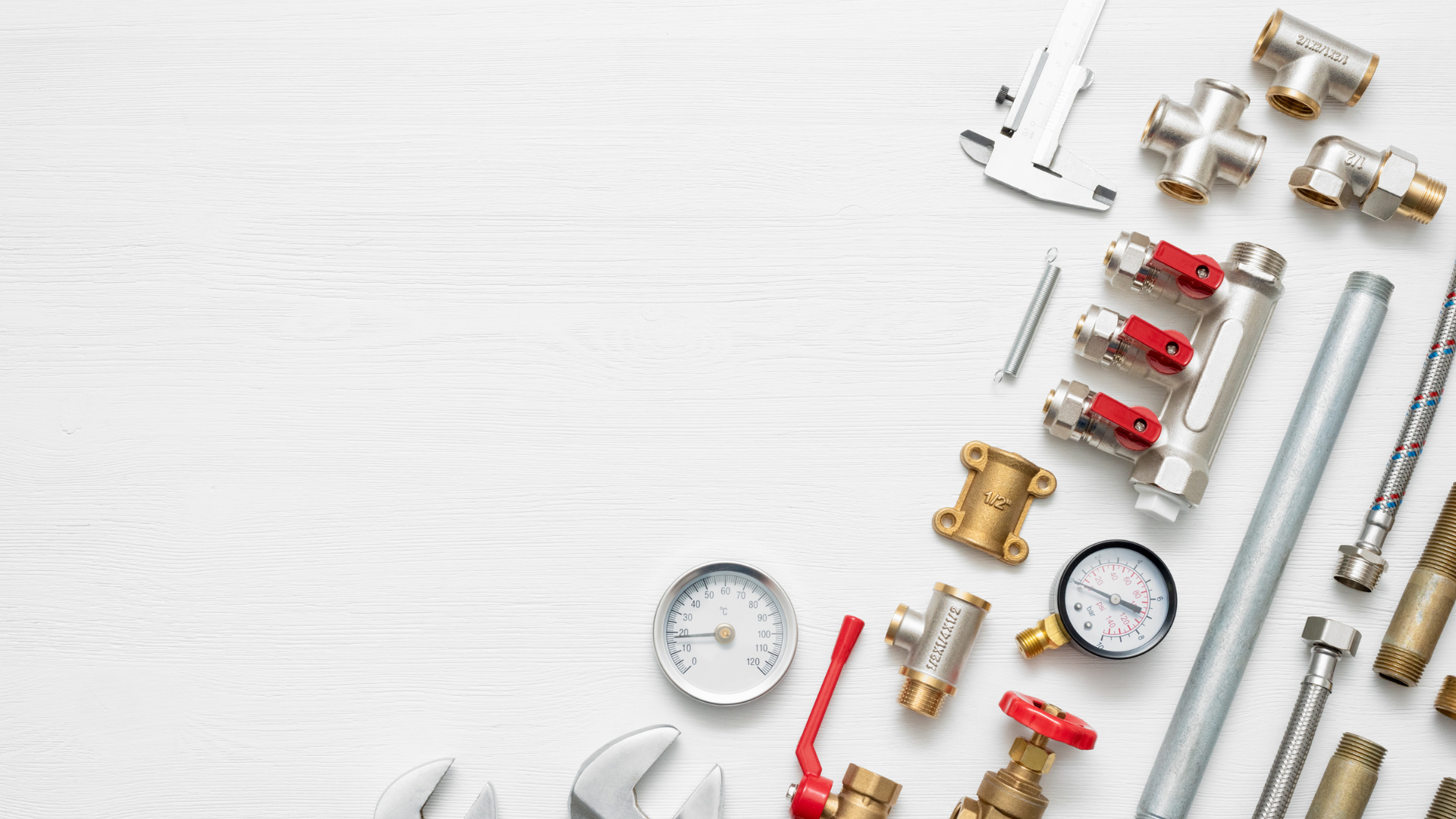 Plumbing tools and components including wrenches, valves, gauges, and pipes arranged on a white background, symbolizing professional plumbing services and repairs.
