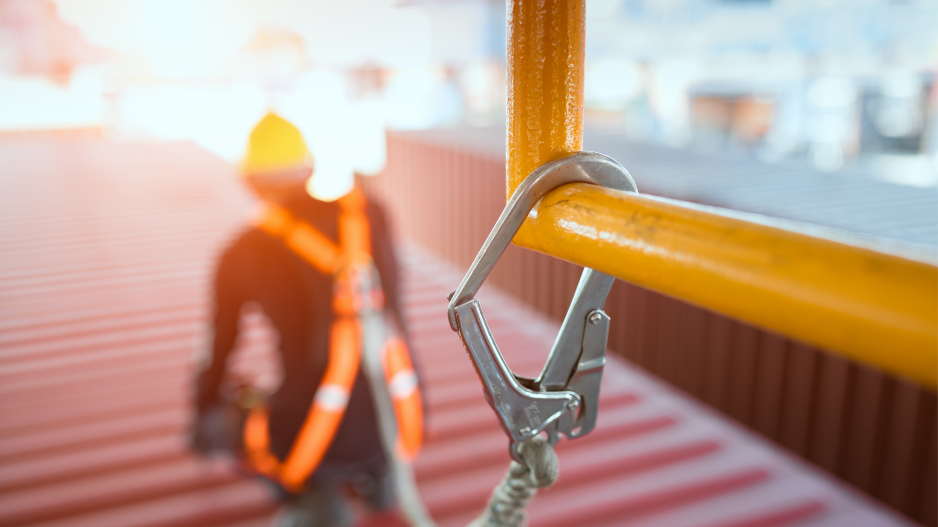 Roof harness attachment to a safety rail, with a blurred worker in a safety harness, highlighting the importance of worker safety and compliance in roofing projects.